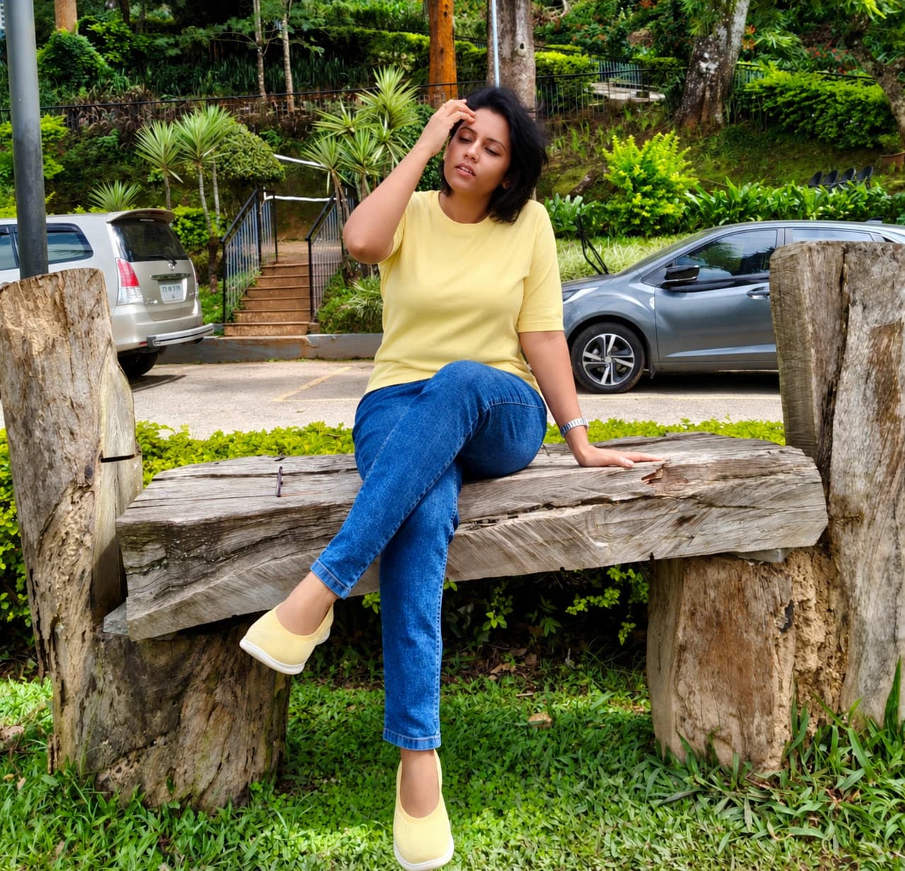Priya seated outdoors beside a tree